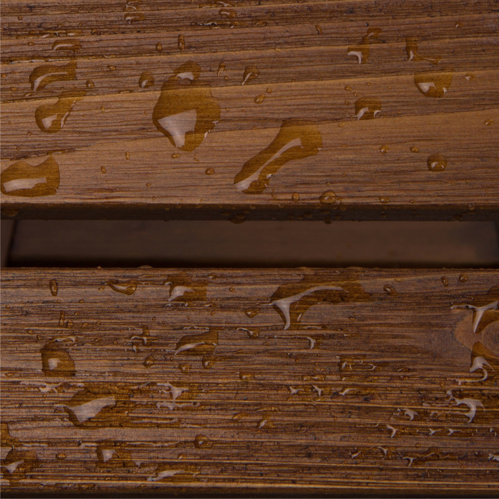 Close-up of a brown wood-grain surface with water droplets beading on top, showing a horizontal seam between two planks.