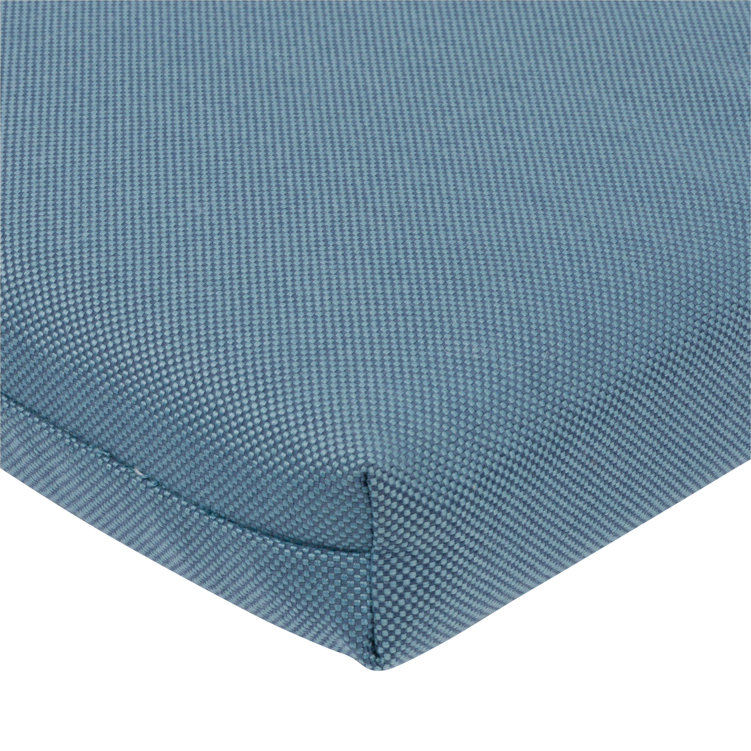 Close-up of a textured blue woven fabric cushion corner with a visible seam on a white background.