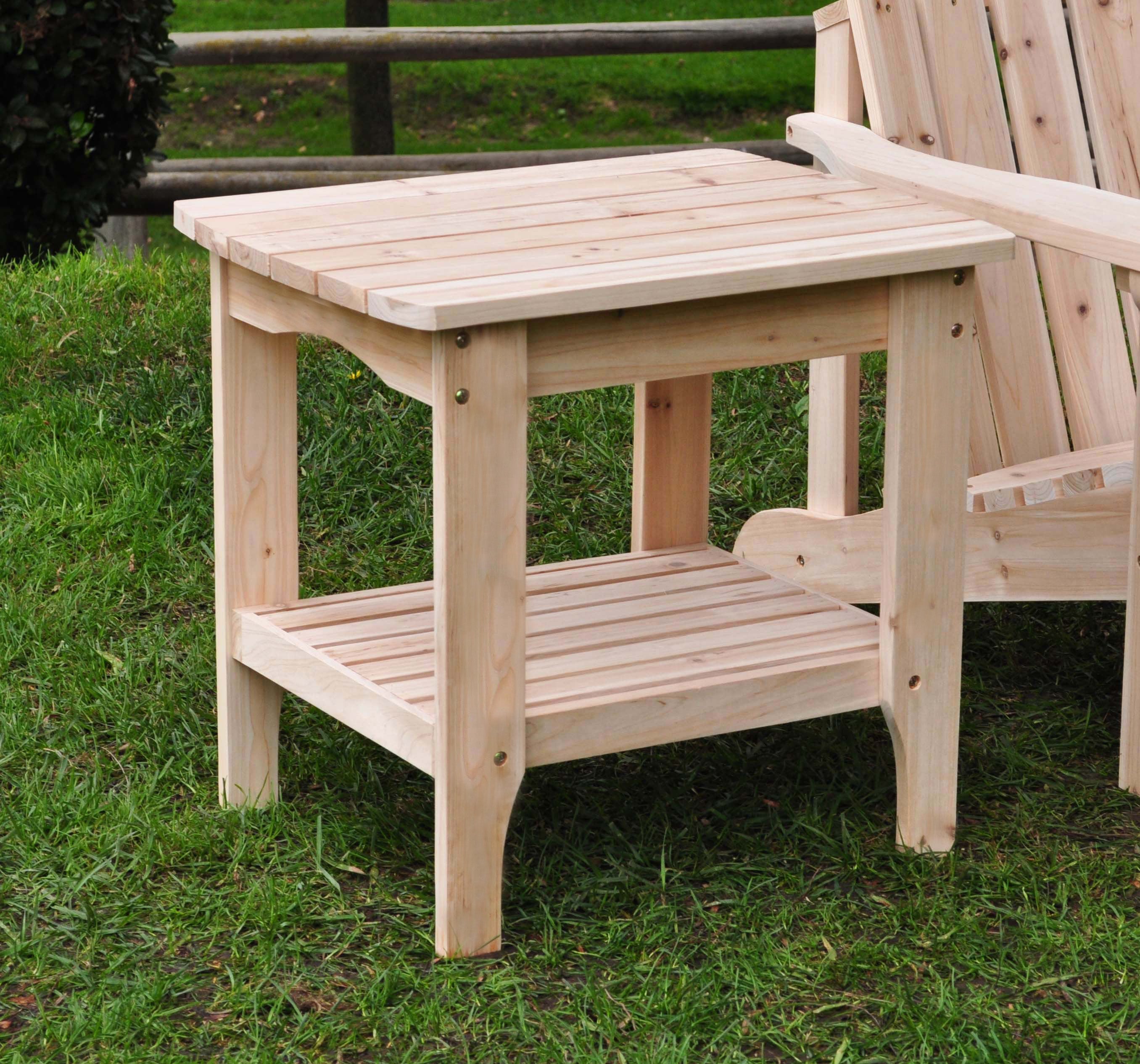 A natural cedar wood two-tier rectangular side table with a slatted top and lower shelf on a grassy lawn. 
