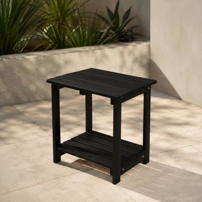 Black outdoor side table on a patio with plants in the background 