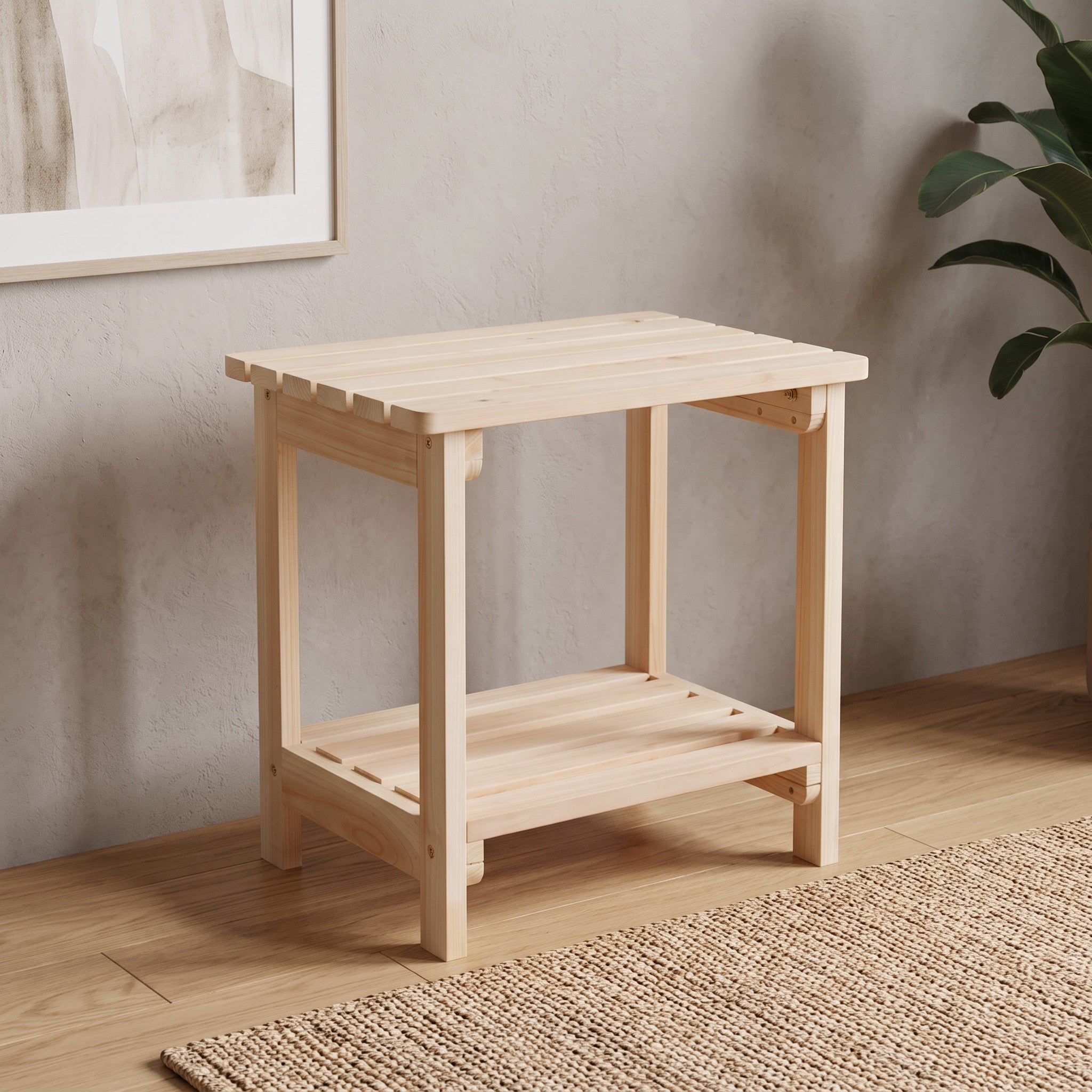 A light natural wood side table with an open lower shelf, shown in a styled room setting with a textured wall, wood floor, and a plant in the background. 