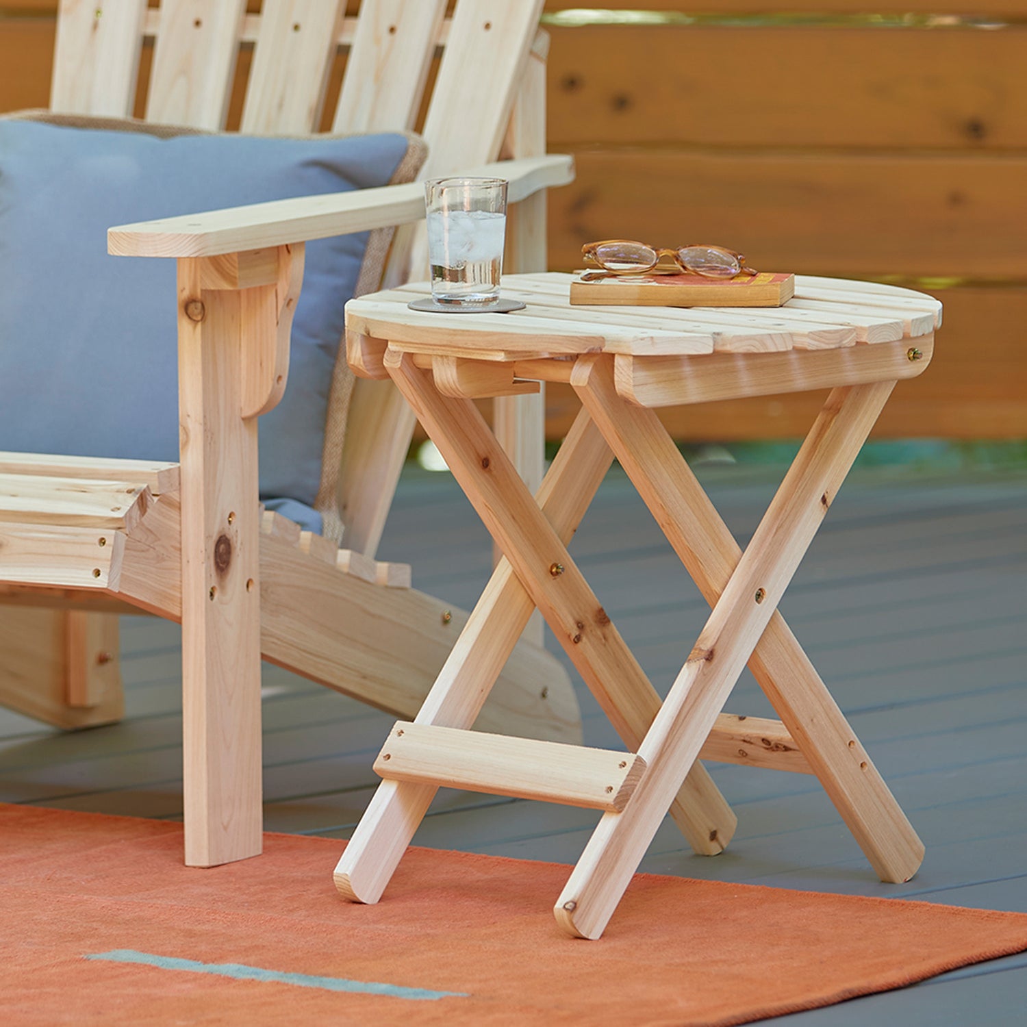 Wooden folding table on a deck with a glass of water and sunglasses. 