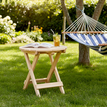 Wooden folding table with a book and drink in a garden setting with a hammock. 