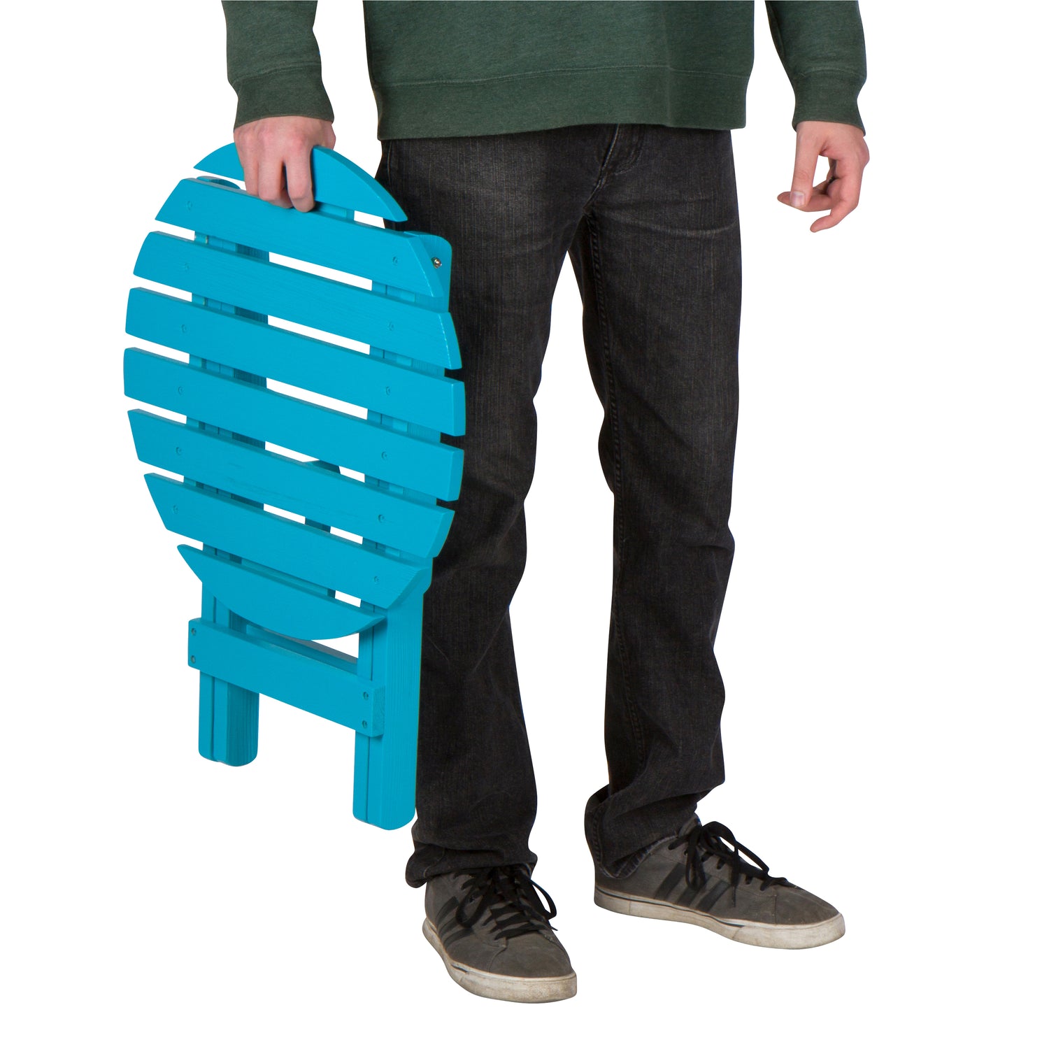 A person wearing a dark green long-sleeve shirt, black jeans, and gray sneakers holds a bright turquoise folding chair against a plain white background. 