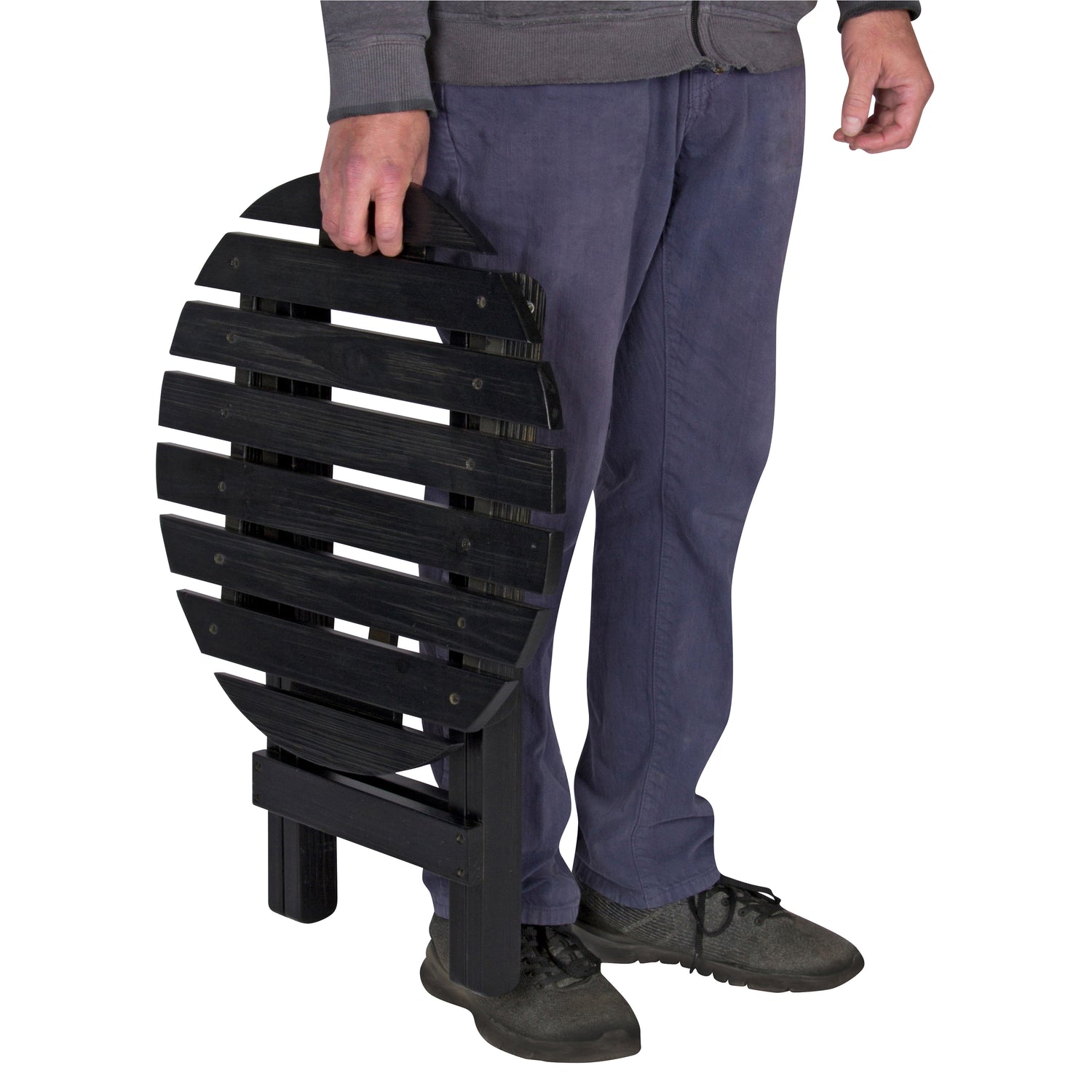 A person holding a black folding slatted bench or chair against a plain white background. 