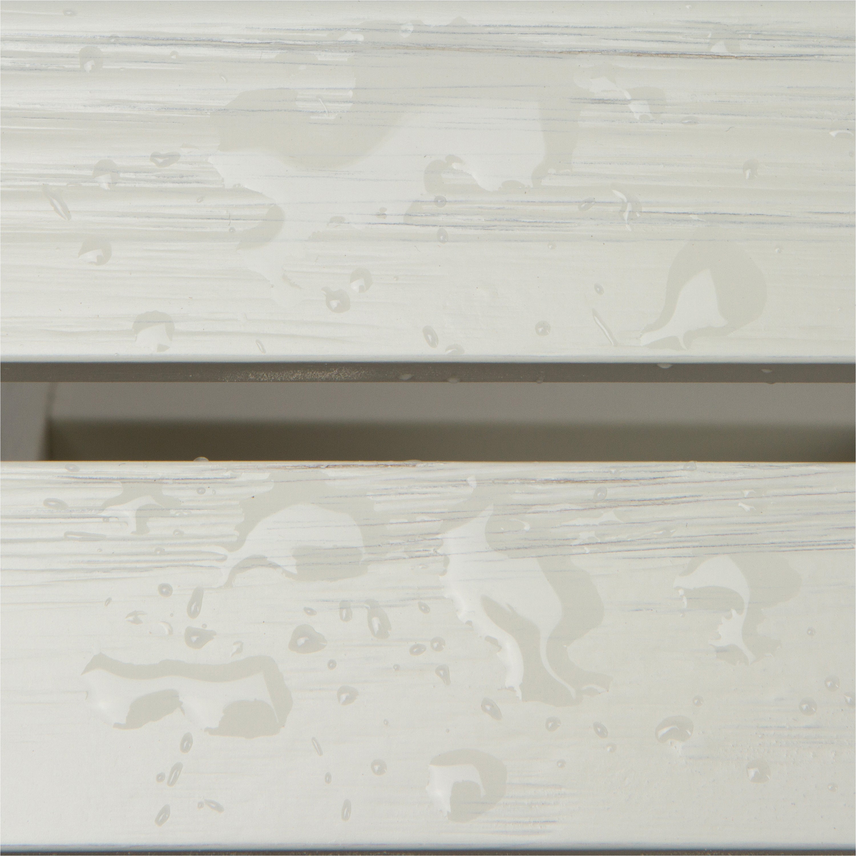 Close-up of a white or off-white wood-look surface with water droplets and streaks, showing a glossy, wet texture. 
