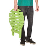 A person holding a lime green folding slatted chair against a plain white background. The person is wearing a green t-shirt, dark gray jeans, and black sneakers. 