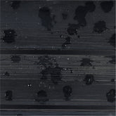 A close-up of a dark charcoal gray ribbed surface with glossy black water droplets and small reflective highlights. 