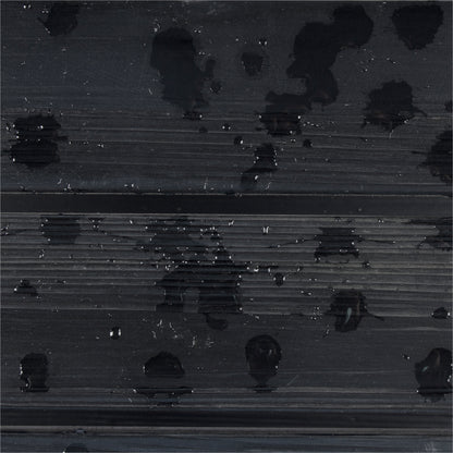 A close-up of a dark charcoal gray ribbed surface with glossy black water droplets and small reflective highlights. 