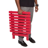 A person holding a bright red folding slatted table against a plain white background. 