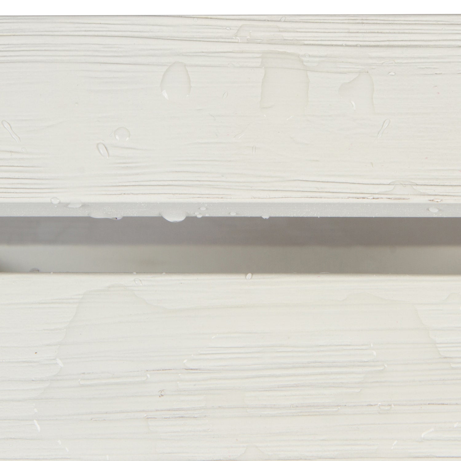 Close-up of a white textured surface with horizontal ridges and a few water droplets, showing a shallow channel or groove in the middle. 
