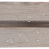 Close-up of a light beige wood-grain surface with clear water droplets beading on top, showing a horizontal seam between two panels.  