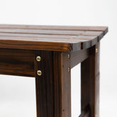 Close-up of a dark brown wooden bench corner showing the slatted top, leg construction, and brass-colored metal screws on a white background. 