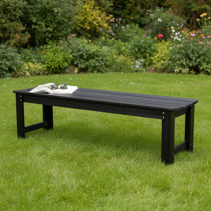 A long black outdoor bench with a slatted wooden top and sturdy legs, placed on a green lawn in a garden setting. An open book and sunglasses rest on the bench. 