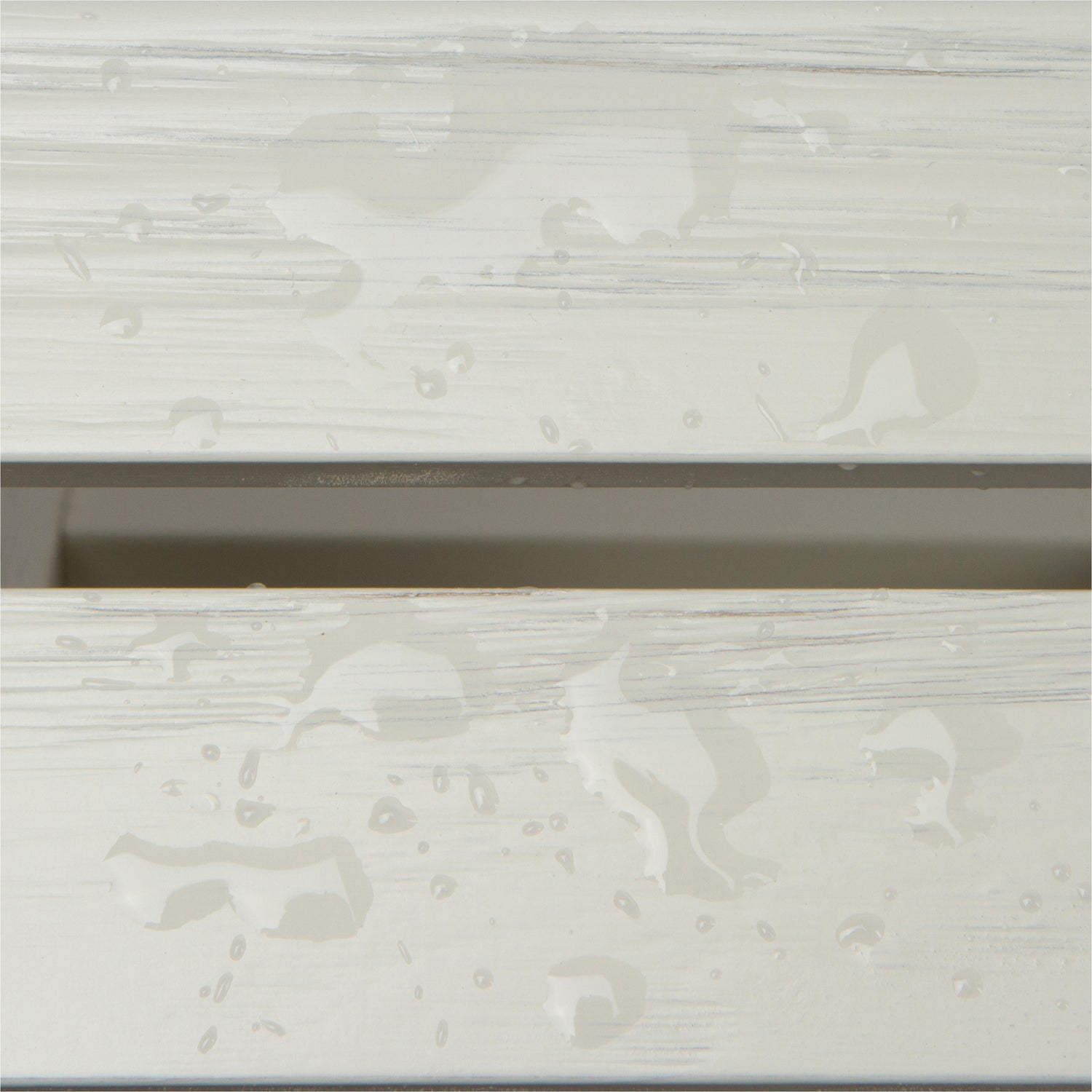 Close-up of a white or off-white wood-look surface with water droplets and streaks, showing a glossy, wet texture. 