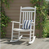 A white outdoor rocking chair with a blue and white striped throw pillow, set on a wooden deck in front of a brown house siding wall with green climbing vines. 