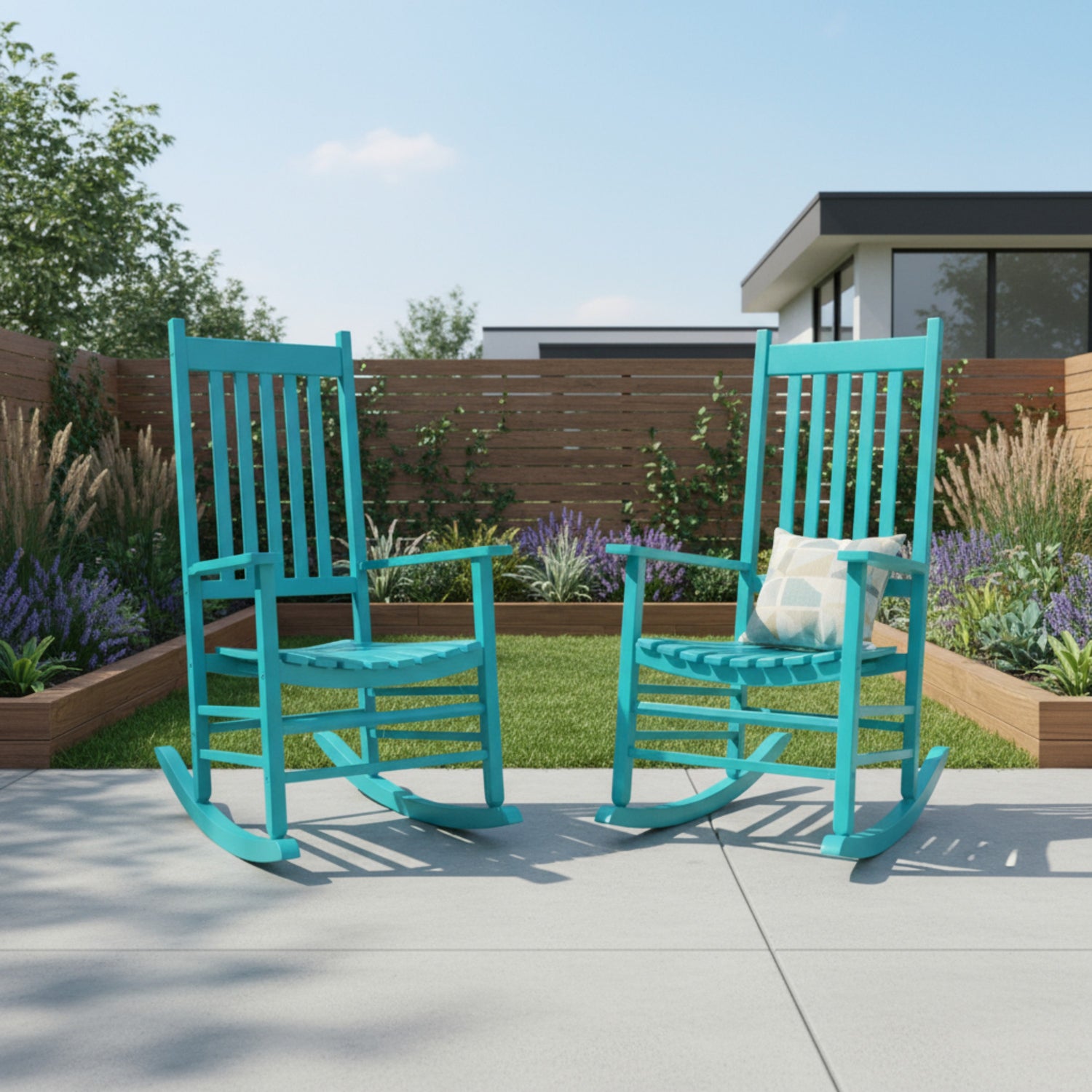 Two turquoise rocking chairs on a patio with a garden and house in the background. 