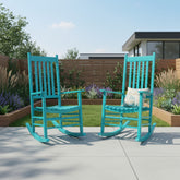 Two turquoise rocking chairs on a patio with a garden and house in the background. 