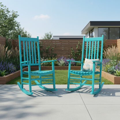 Two turquoise rocking chairs on a patio with a garden and house in the background. 