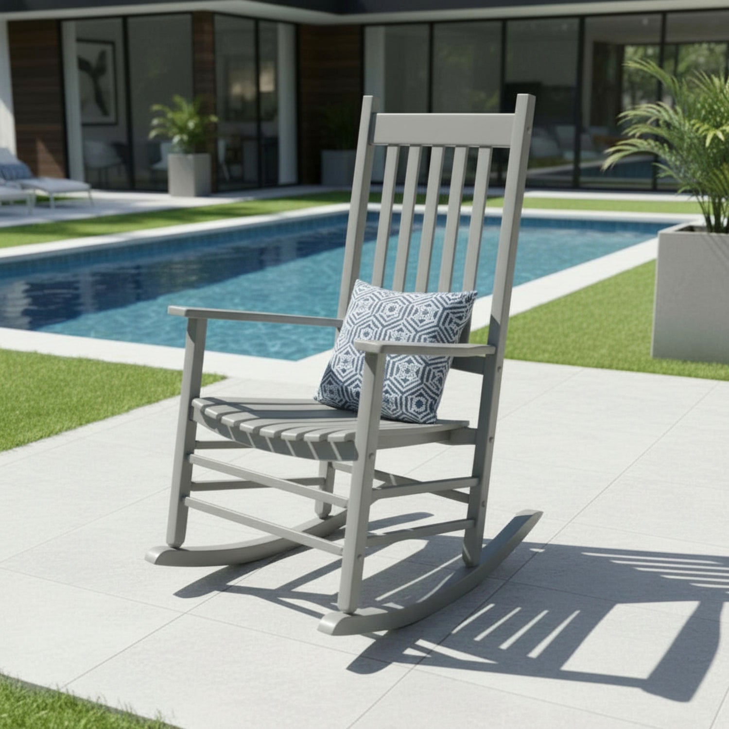 Gray rocking chair with a patterned pillow by a poolside 
