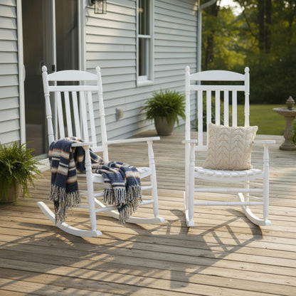 Two white outdoor rocking chairs on a wooden deck in front of a light gray house. One chair has a navy, beige, and white striped throw blanket draped over it, and the other has a beige chevron-patterned pillow. 
