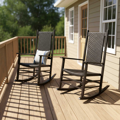 Two outdoor rocking chairs on a wooden deck next to a house, with one chair featuring a striped pillow. 