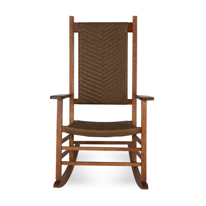 A wooden rocking chair with a tall woven brown wicker backrest and seat, shown against a plain white  background. 