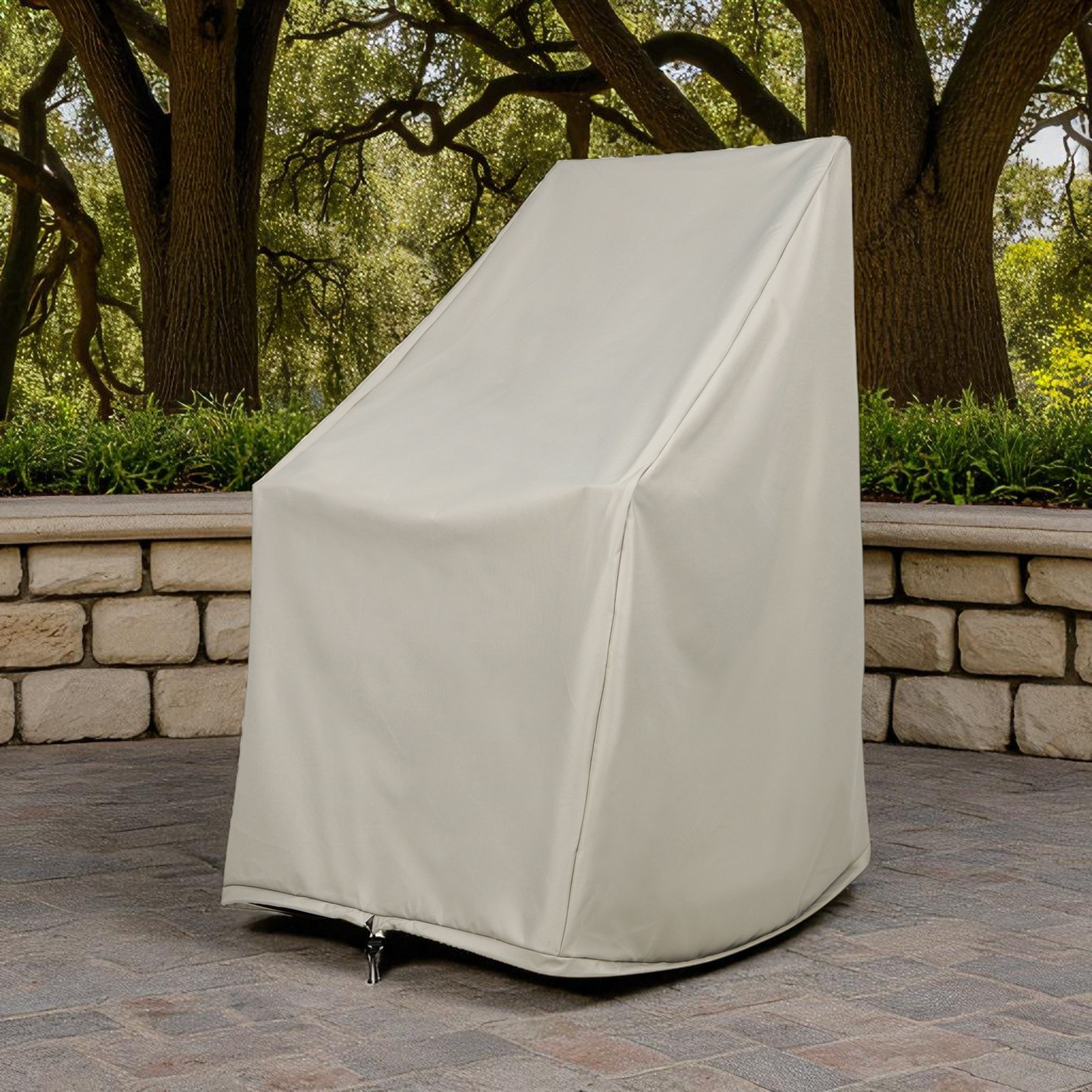 A gray furniture cover, likely for a patio chair or small table, shown standing on a stone patio in front of a stone wall and trees. 