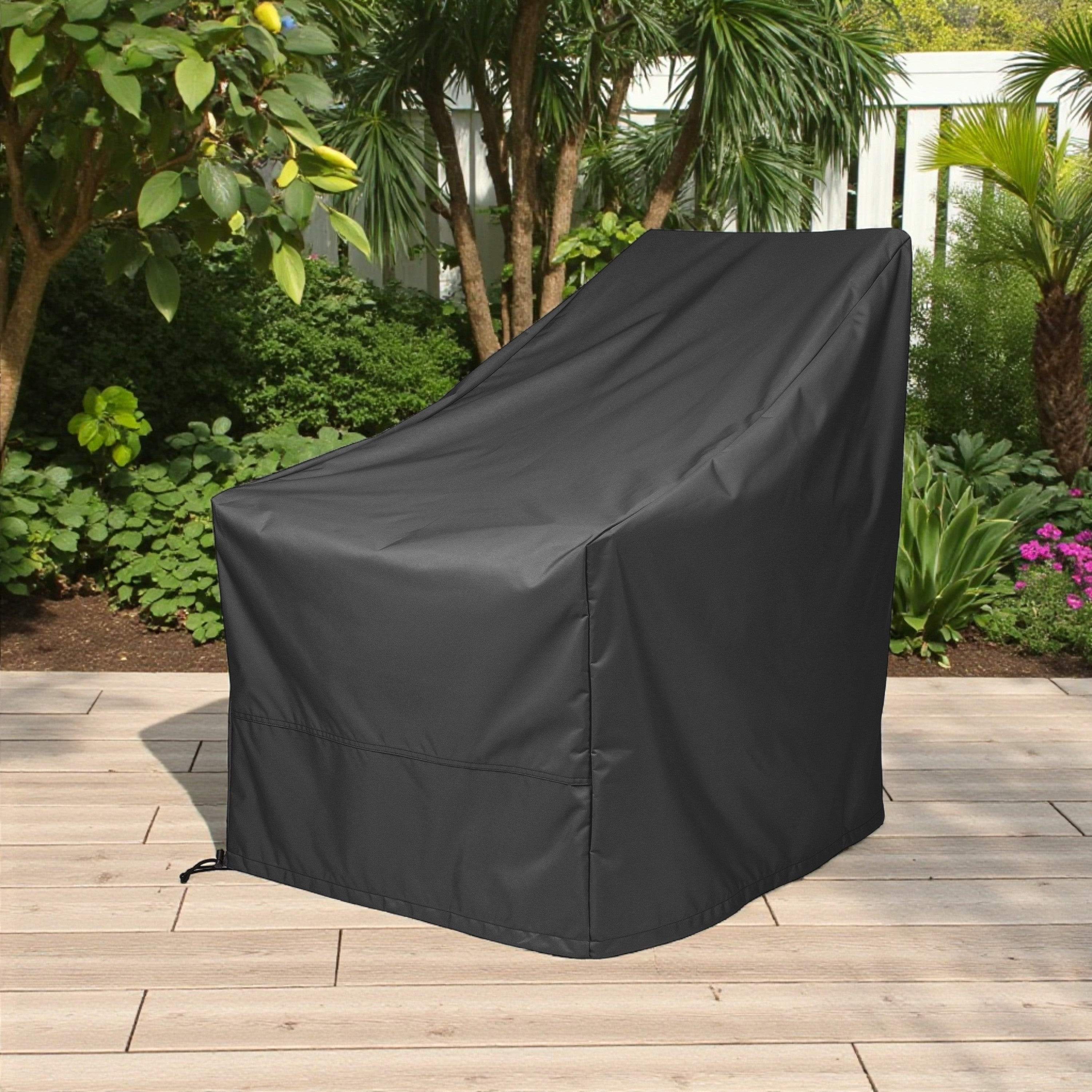 A black outdoor patio chair cover standing on a light wood deck in a garden setting with plants and trees in the background. 