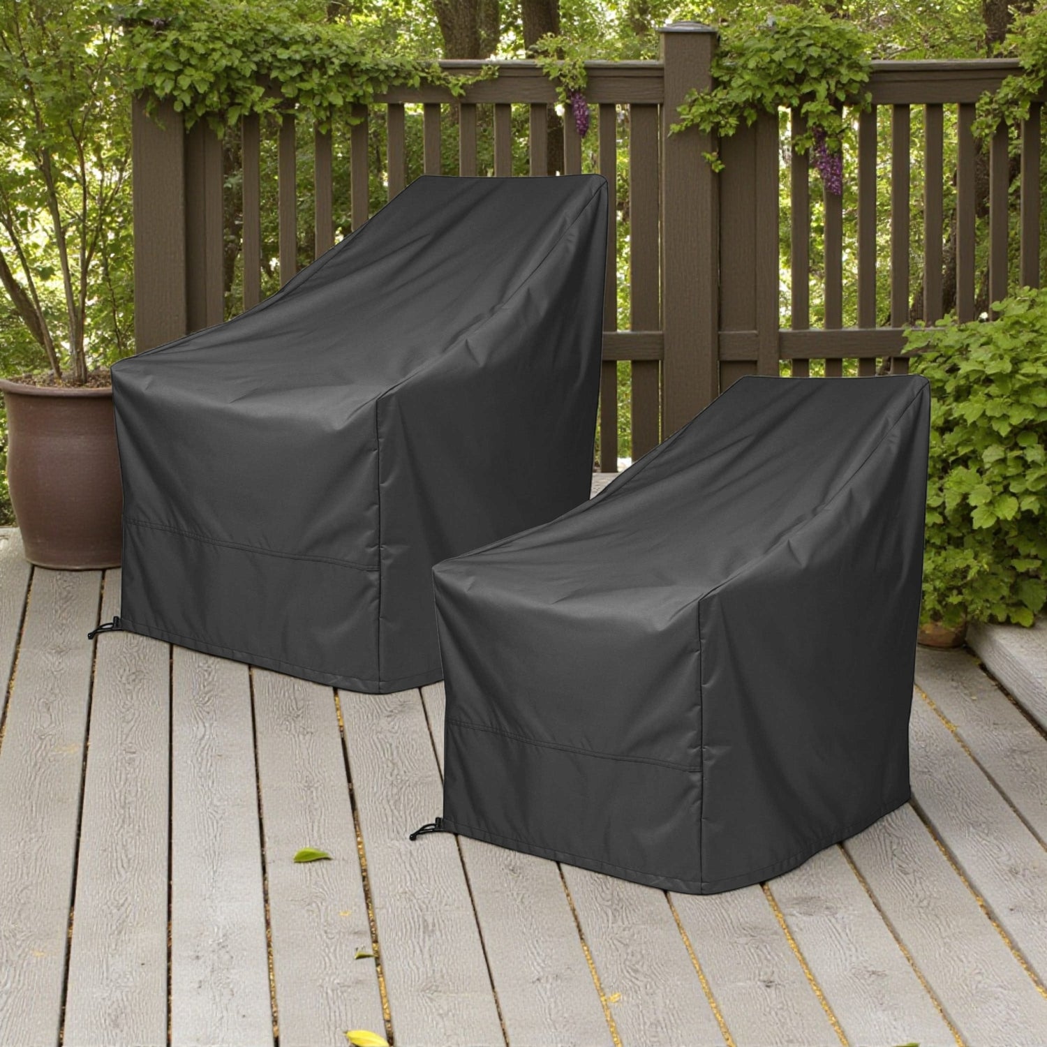 Two black outdoor patio chair covers on a wooden deck with a brown fence and green plants in the background. 