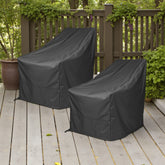 Two black outdoor patio chair covers on a wooden deck with a brown fence and green plants in the background. 