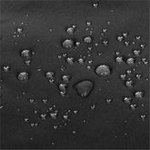 Close-up of a dark textured fabric surface with scattered water droplets showing a water-repellent or hydrophobic effect. 