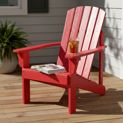 A red Adirondack-style outdoor chair on a wooden deck with a glass of iced tea on the armrest and an open magazine on the seat. 