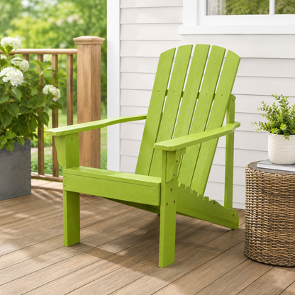 A bright lime green outdoor Adirondack chair on a wooden deck next to a white house wall, with a wicker side table and potted plants nearby. 