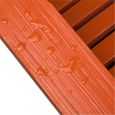 Close-up of an orange textured slatted surface with water droplets beading on top, showing a glossy, ribbed finish. 