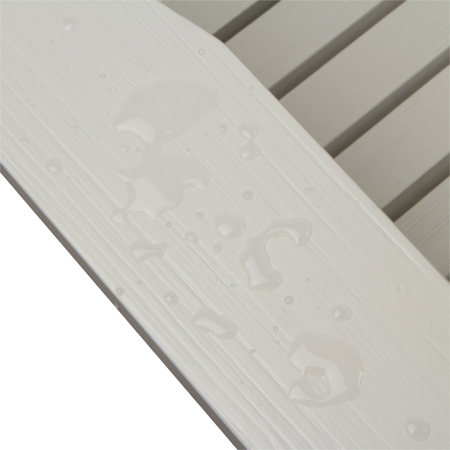 Close-up of a white textured slatted surface with water droplets on a white background. 