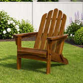 A brown wooden Adirondack-style outdoor chair on a green lawn with a white fence and garden plants in the background. 