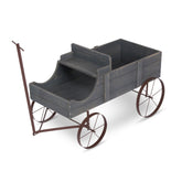 A rustic wooden display cart with a dark gray weathered finish, featuring a step-up rear platform and a brown metal wheeled frame with a handle.  
