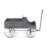 A rustic wooden toy wagon or cart with a weathered gray painted wood body, dark metal frame, and large spoked wheels, shown on a plain white background. 