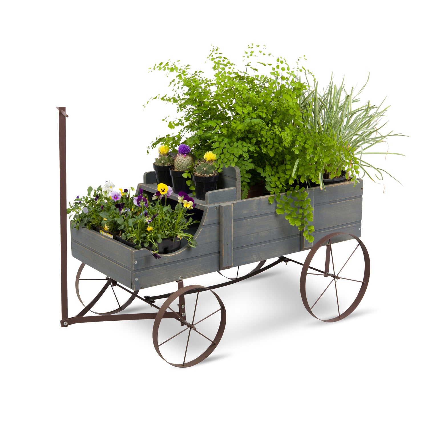 A rustic gray wooden wagon planter with dark metal wheels and a vertical hitch arm, filled with green plants and small potted flowers, shown on a white background. 