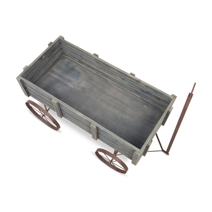 A rustic wooden wagon or cart with a weathered gray-brown finish, featuring two small spoked wheels and a long metal pull handle, shown on a plain white background. 