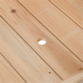 Close-up of a light natural wood slatted surface with visible wood grain, knots, and a circular cutout in the center. 