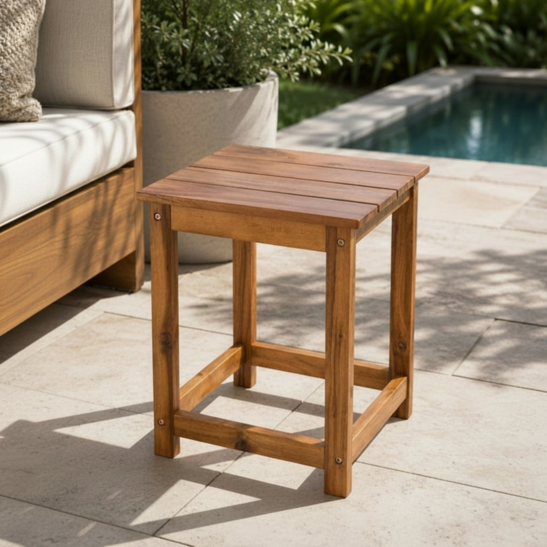 Wooden side table on a patio with a pool and outdoor furniture in the background 
