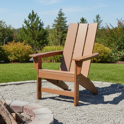 A brown outdoor Adirondack-style chair placed on a gravel patio with a grassy lawn, trees, and blue sky in the background. 