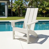 A white outdoor Adirondack-style lounge chair positioned on a light concrete patio next to a swimming pool, with palm trees and a house in the background. 