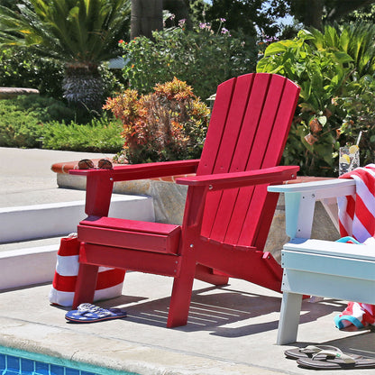Red Adirondack chair by a pool with a striped towel and sandals on a sunny day. 
