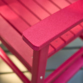 Close-up of a red slatted outdoor chair showing the armrest corner and frame construction. 