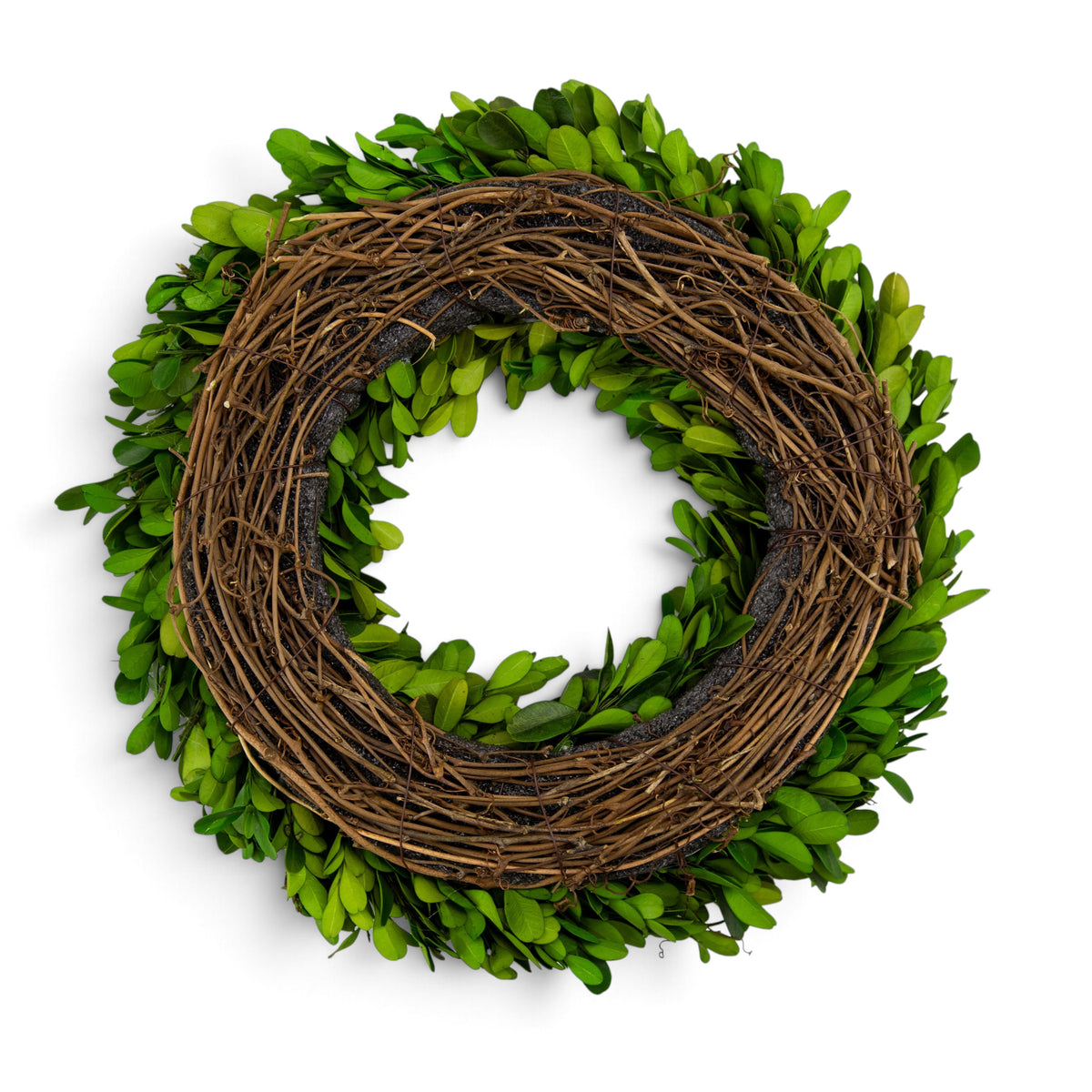 A circular decorative wreath made of intertwined brown twigs with bright green boxwood leaves around the edge, shown on a plain white background.