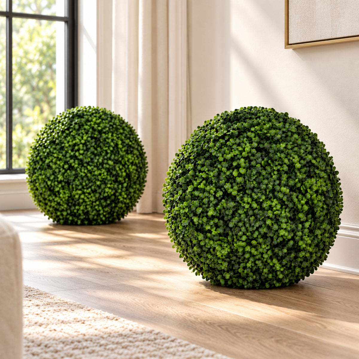 Two round green faux topiary tree planters placed on a light wood floor in a bright living room setting.